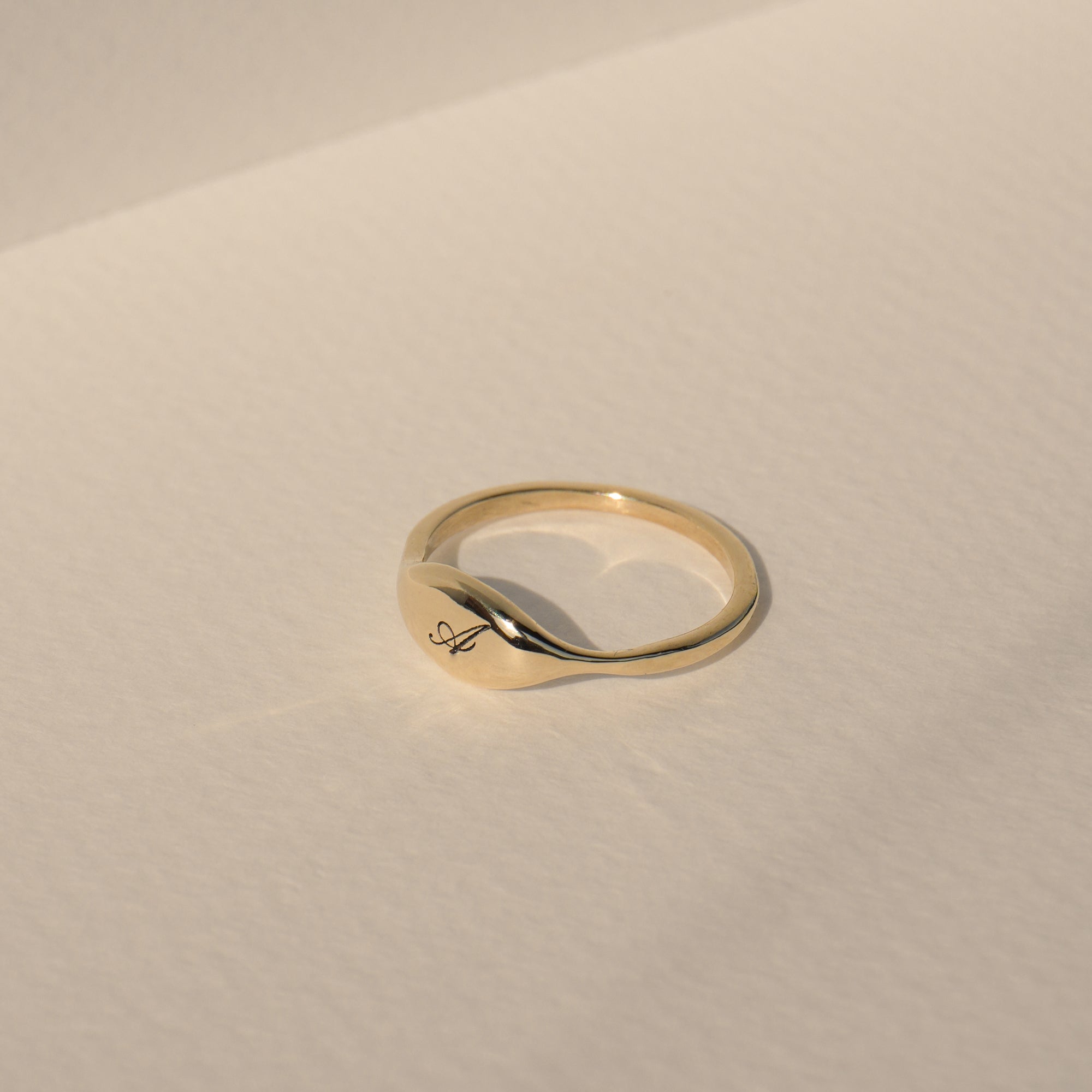 Close up of puffy signet face on solid gold initial ring by Vivi Ami