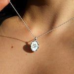 Silver necklace with a pendant and rope chain on a person's neck