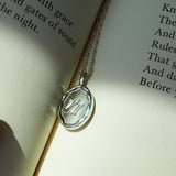 Silver pendant with engraved initials on an open book